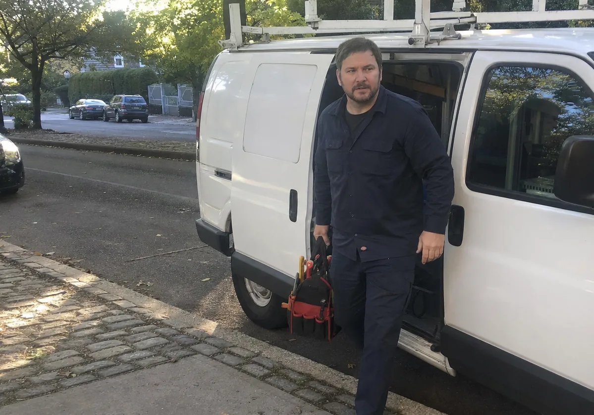 Street-level frame of a service van pulled up outside an older home with steps to the front door